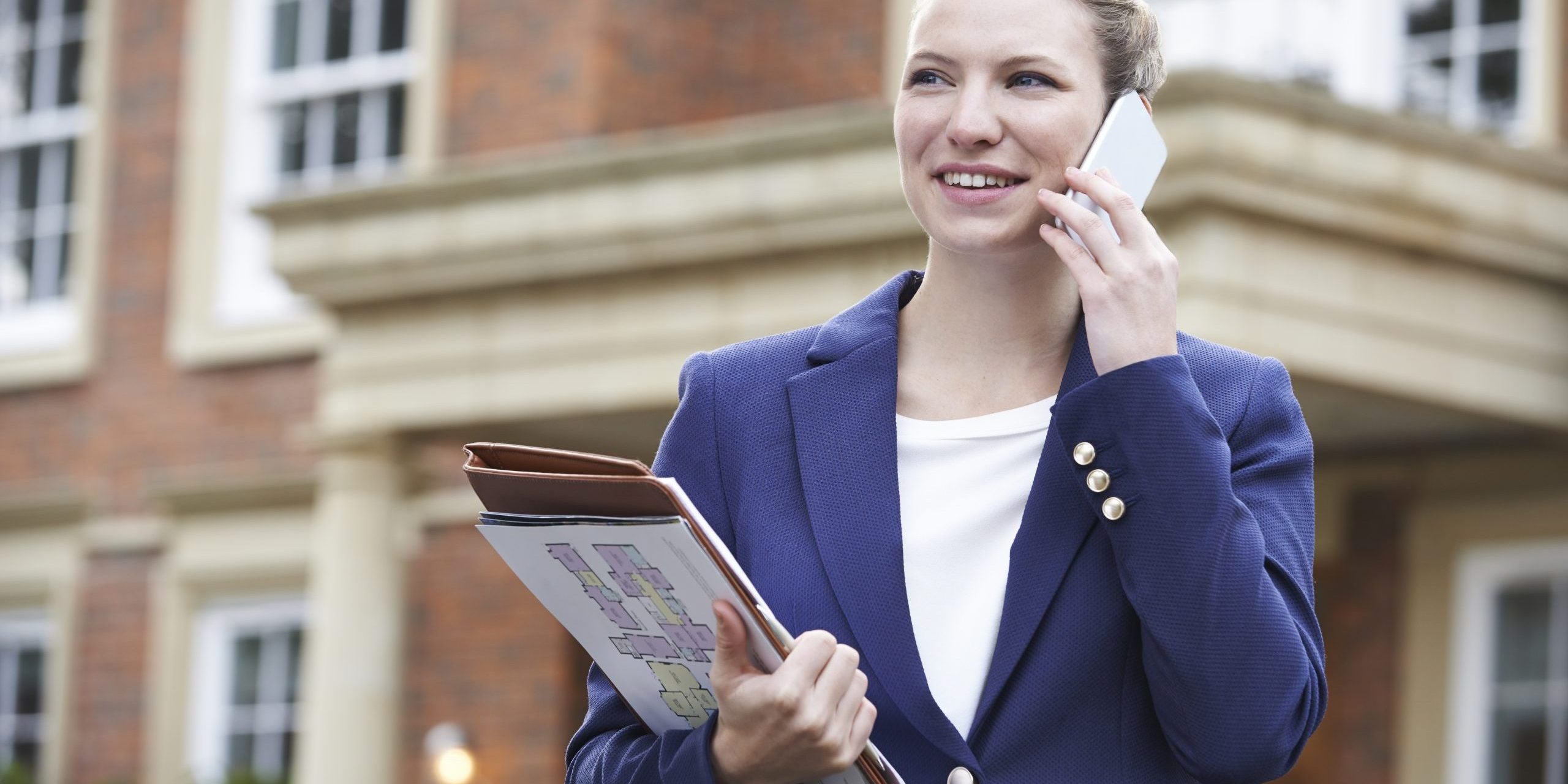 Female Realtor On Phone Outside Residential Property