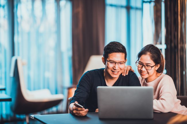 Young Asian married couple working together using laptop at home or modern office with copy space. Startup family business, SME entrepreneur, business partner, love relationship, or freelance concept Owners corporation works